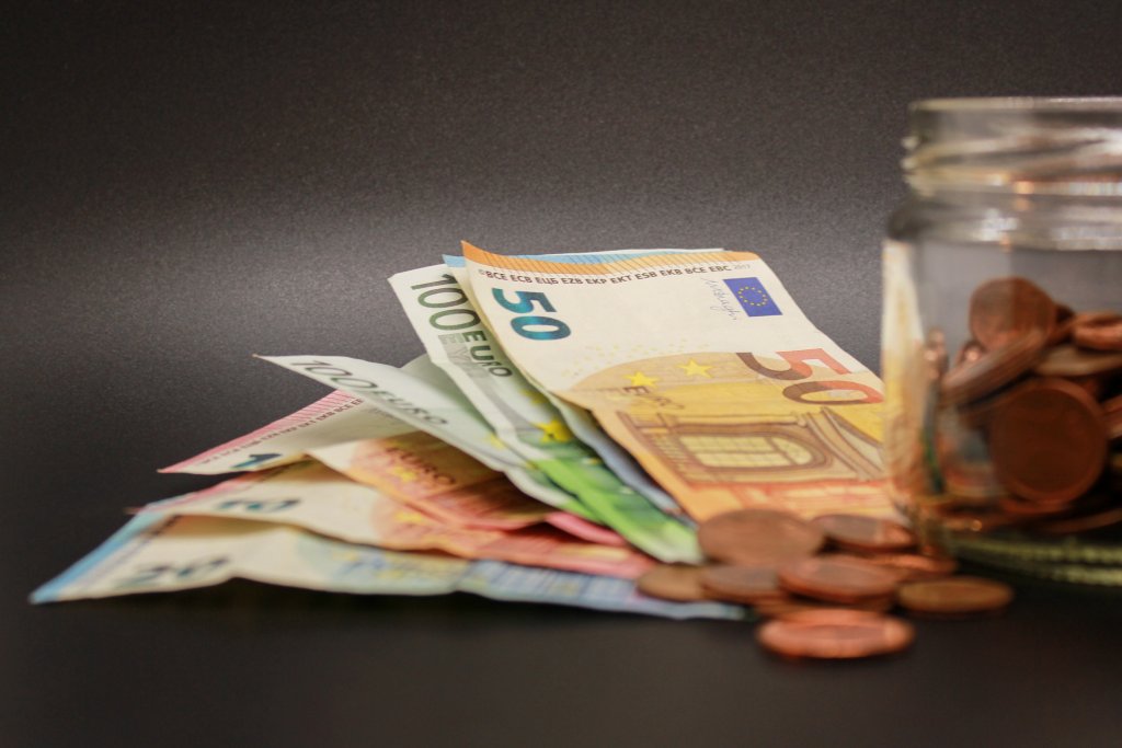 novčanice i kovanice eura pored staklenke s kovanicama