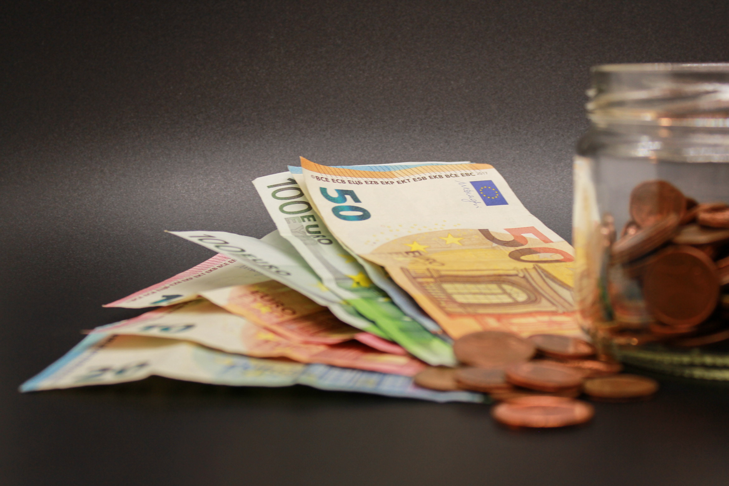 novčanice i kovanice eura pored staklenke s kovanicama