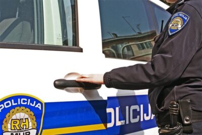 Policajac u uniformi otvara policijski kombi, maricu.