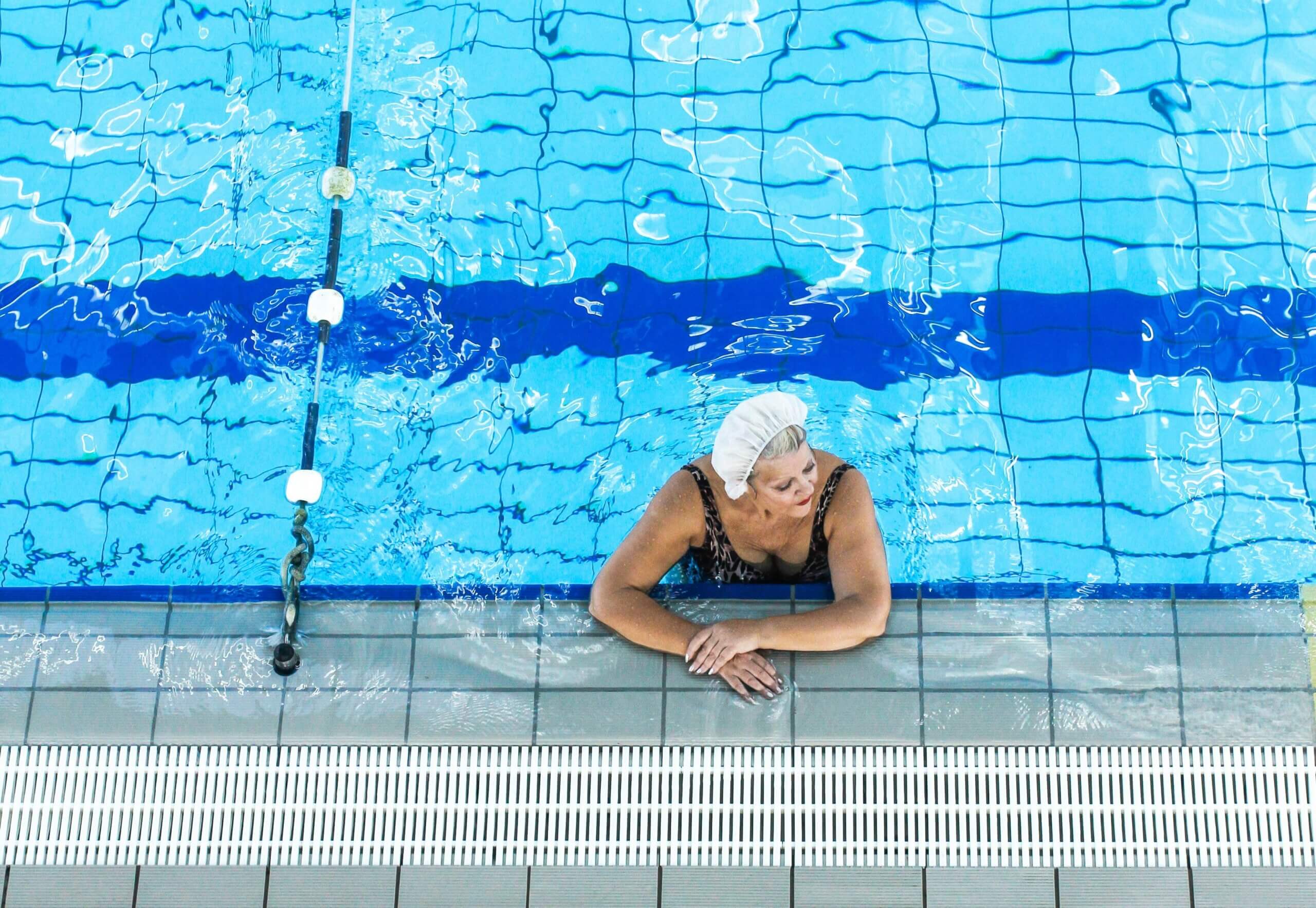 Starija ženska osoba s kapom na glavi u bazenu