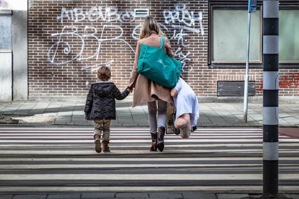 Majka i sin se drže za ruke dok prelaze pješački prijelaz.