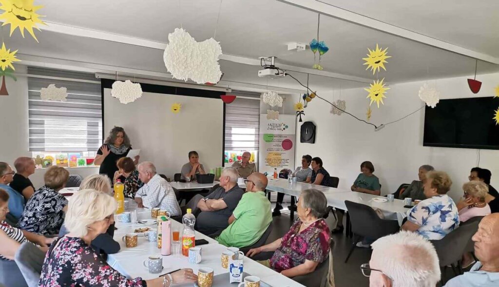 Umirovljenici sjede na stolovima i slušaju predavanje