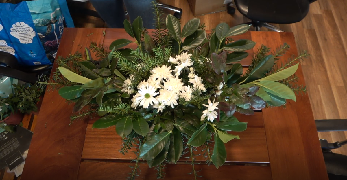 Cvjetni aranžman od bijelog cvijeća i zelenog lišća i iglica